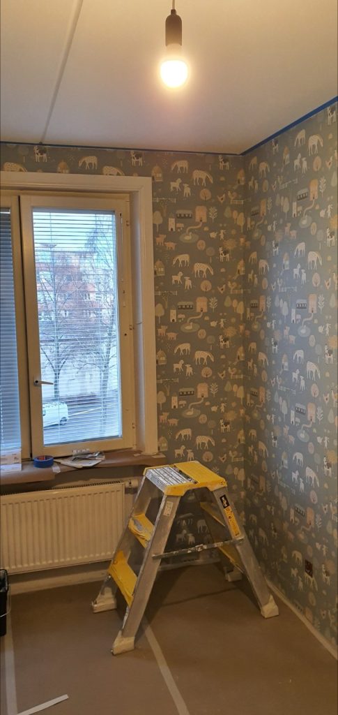 Tapetsering i Stockholm - Arbetet pågår - tapeten passas in kring hörn och fönsternisch.